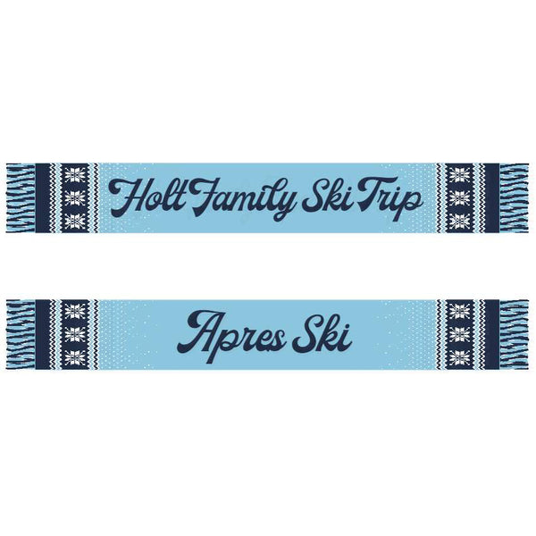 A blue scarf with white text 'HOLT FAMILY SKI TRIP' and 'APRES SKI' along with a ski and snowflake pattern near the fringe.